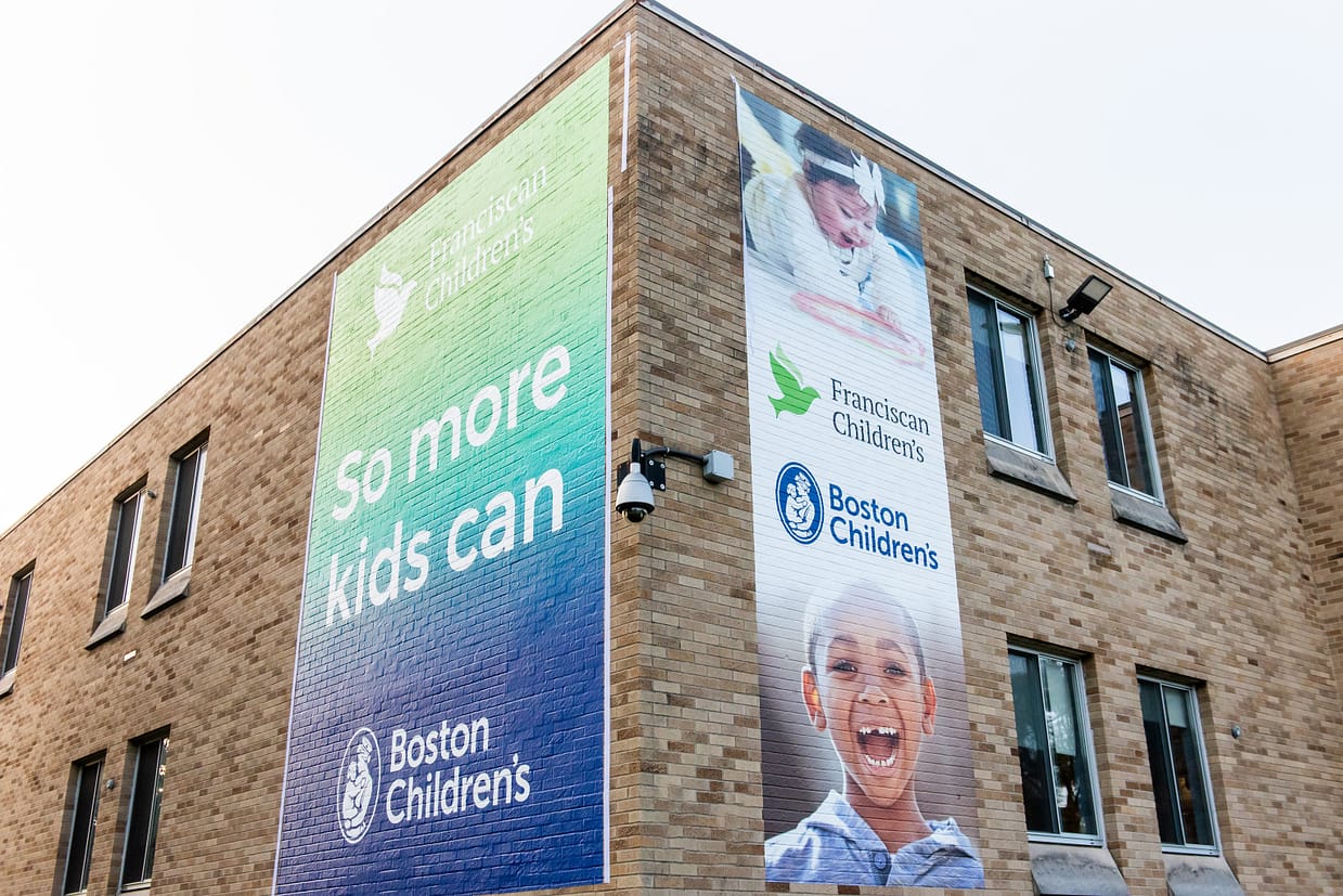 a brick building with posters for boston childrens and franciscans children