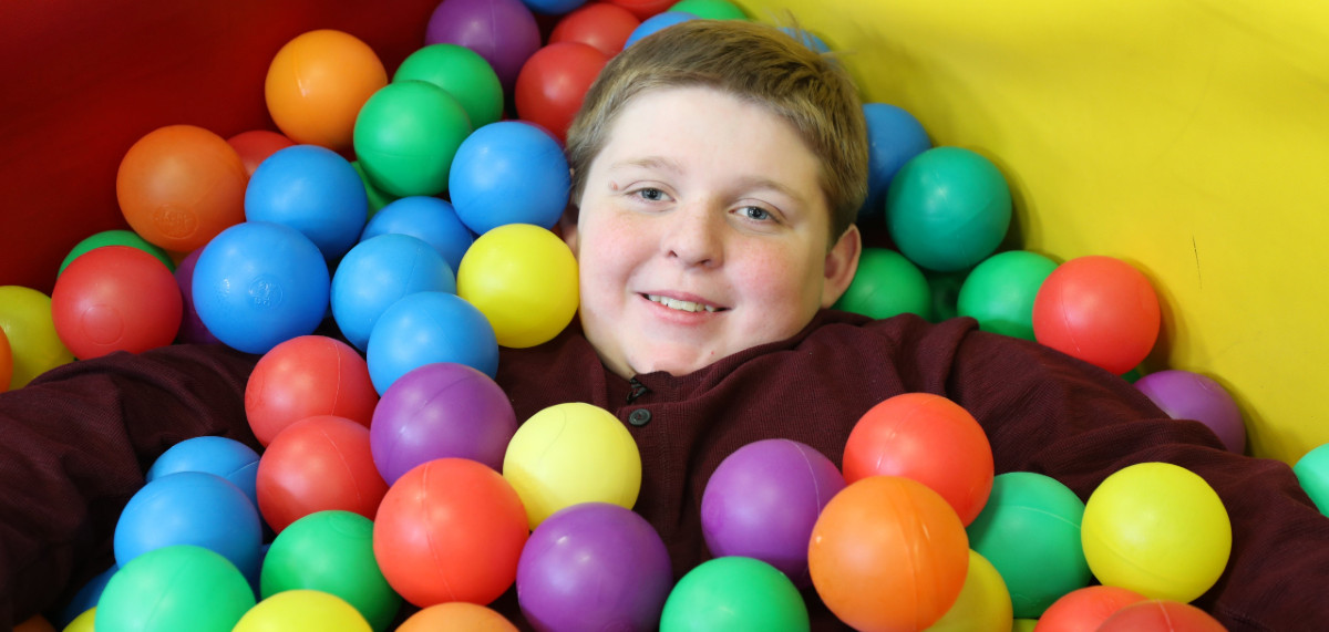 a boy in a colorful ball pit
