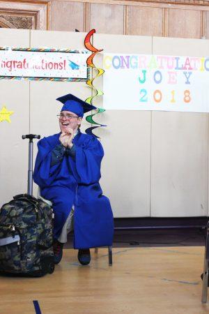 a teenage boy on stage with a graduation cap and gown