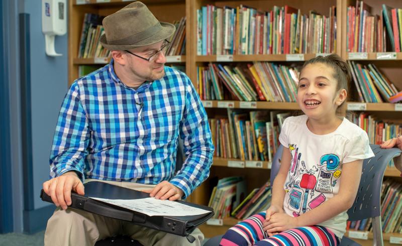 a man holding a book while a young girl sits next to him